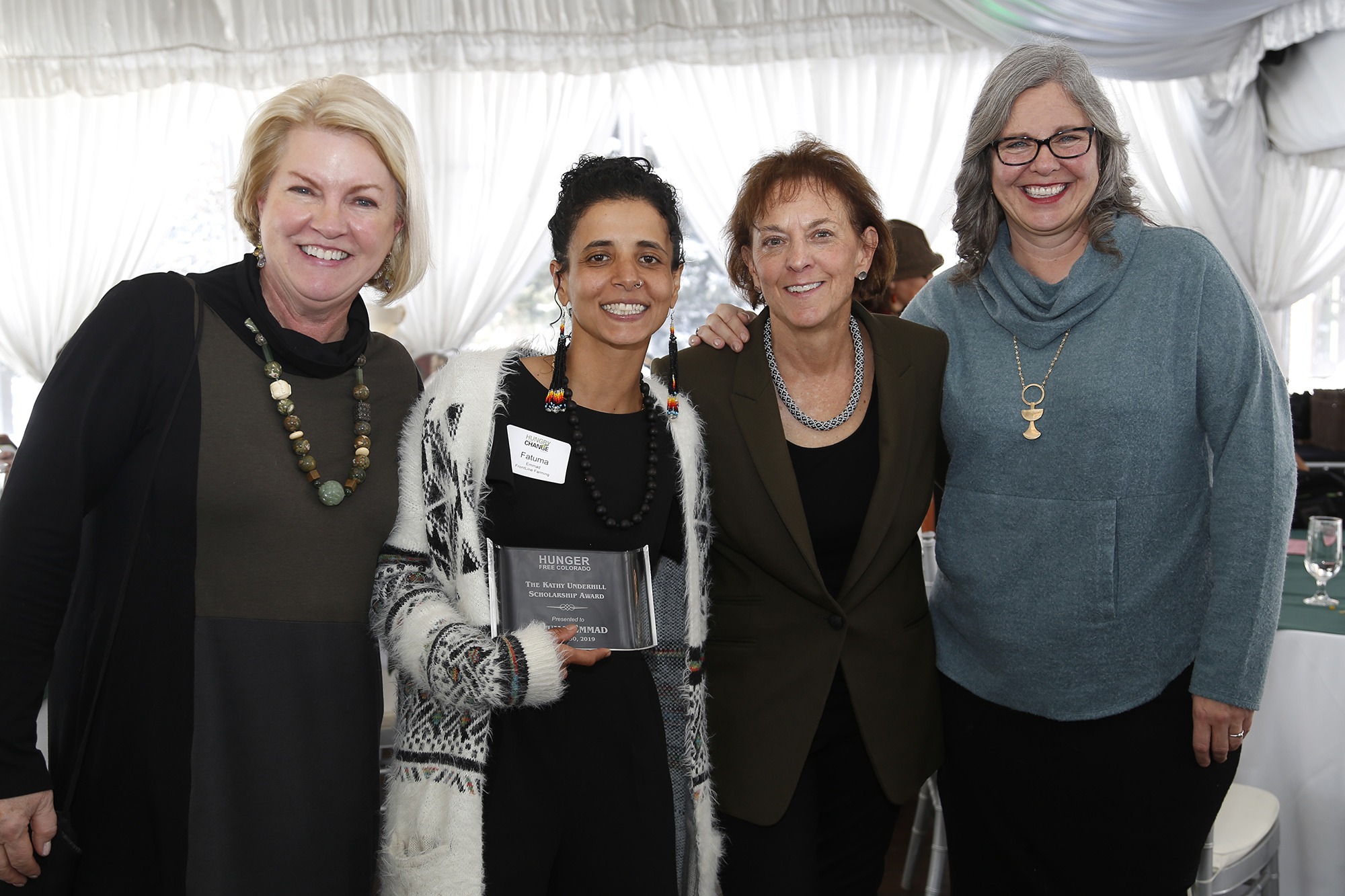 Four women smile and side-hug. The second to the left holds a clear award that says "The Kathy Underhill Scholarship award"