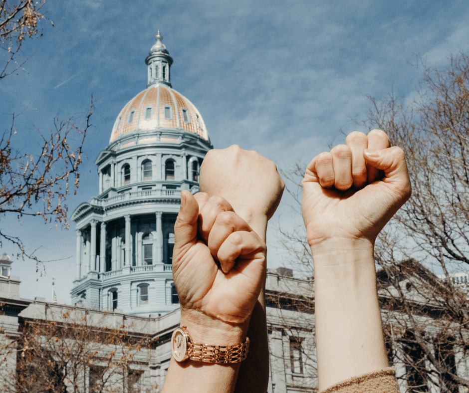 Three firsts clenched in front of the Colorado State capitol building