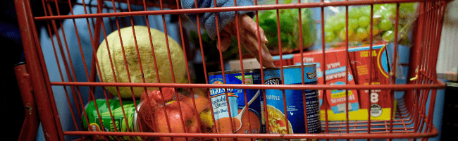 Person places soup can in red grocery cart
