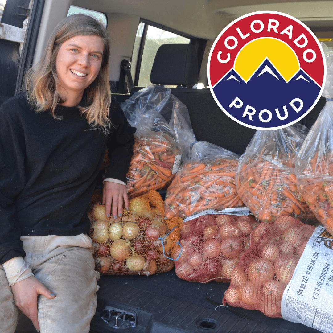 Woman sits in trunk of van next to clear bags of onions and carrots. Colorado Proud logo sits in top right corner