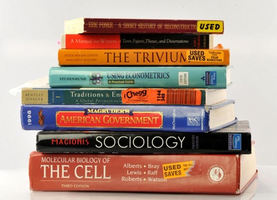 Books about economics, sociology, biology, writing and more are stacked (many have stickers that say used on them)