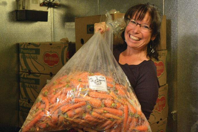 Woman is smiling holding a big bag of carrots