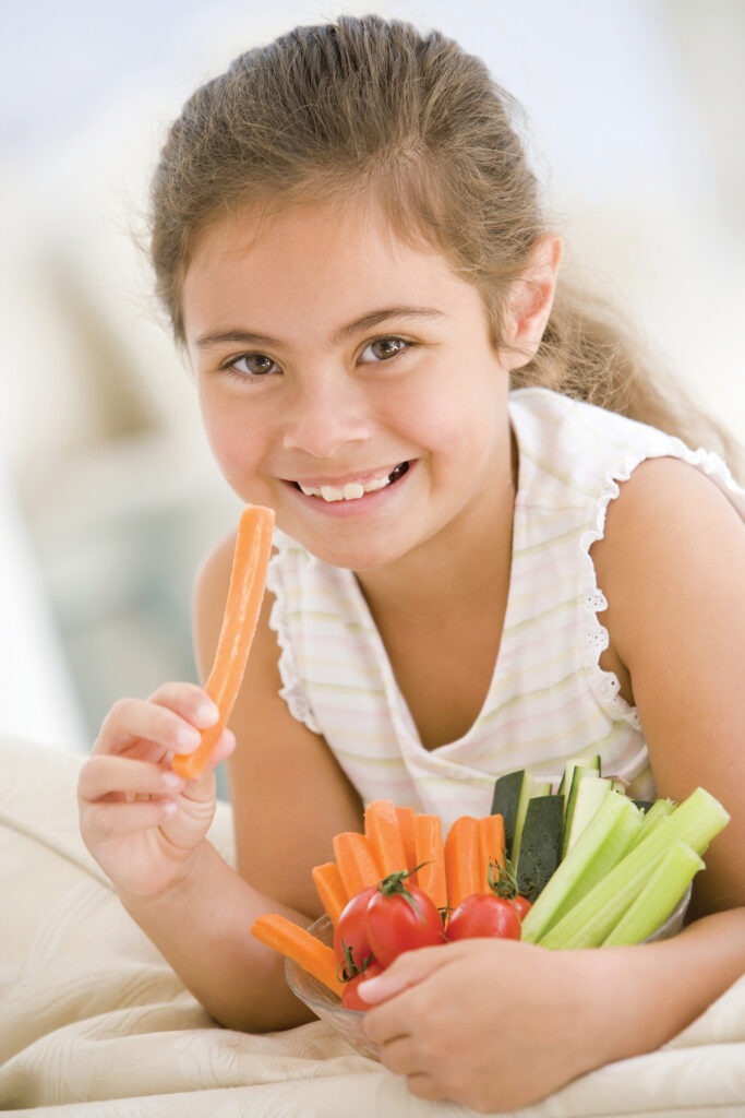 Girl holds vegetables in her hands and eats a carrot