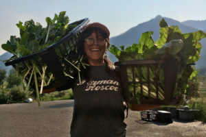 Woman smiles while holding two baskets of large beets.