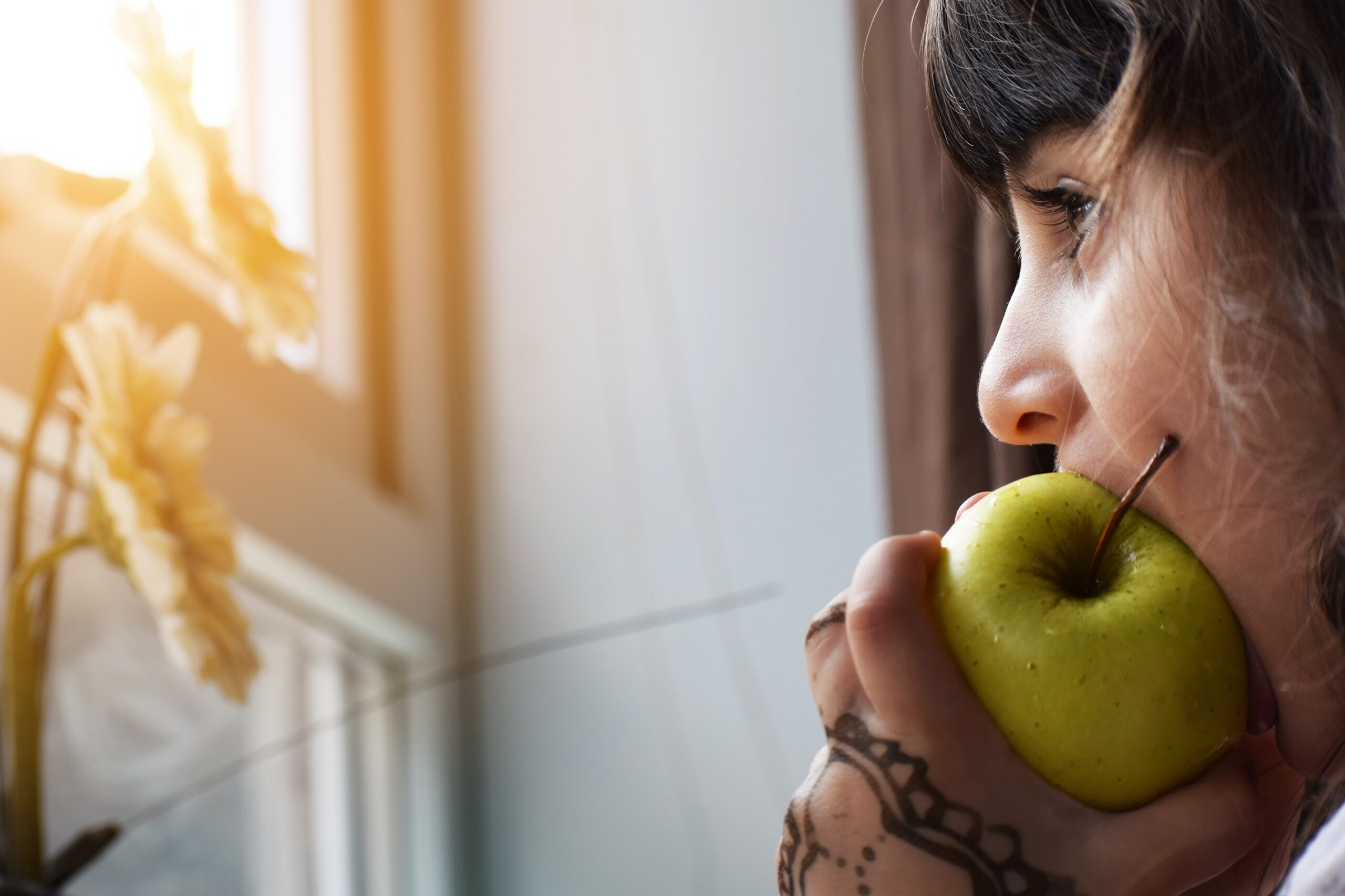 girl eating apple while looking out window